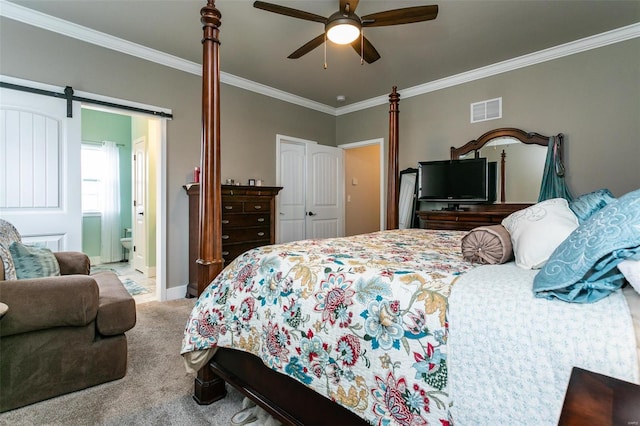 carpeted bedroom featuring crown molding, a barn door, connected bathroom, and ceiling fan