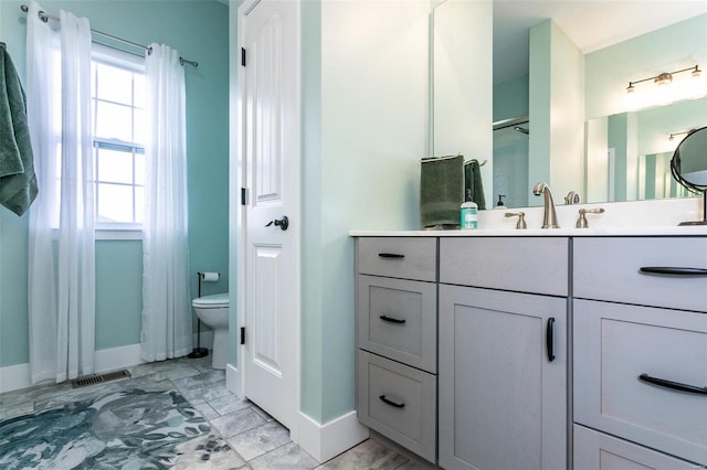 bathroom featuring a healthy amount of sunlight, toilet, and vanity