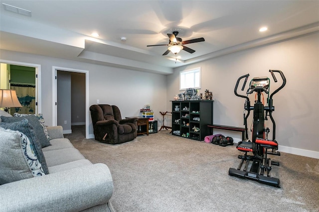 workout room with a tray ceiling, ceiling fan, and carpet