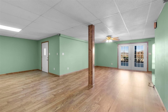 basement featuring a paneled ceiling, ceiling fan, light hardwood / wood-style floors, and french doors