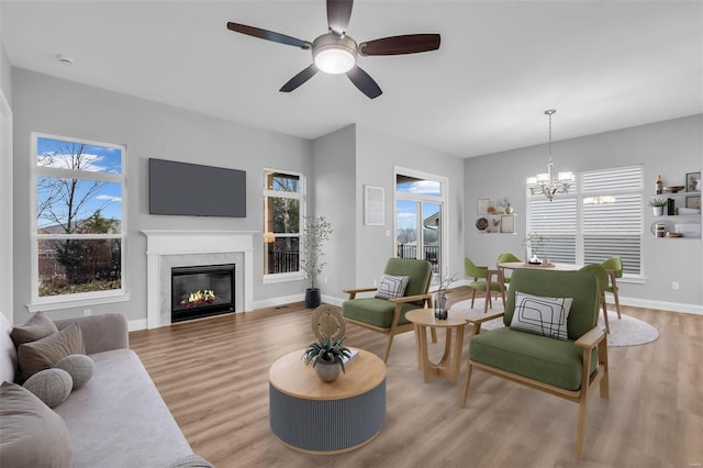 living room with ceiling fan with notable chandelier and light hardwood / wood-style floors