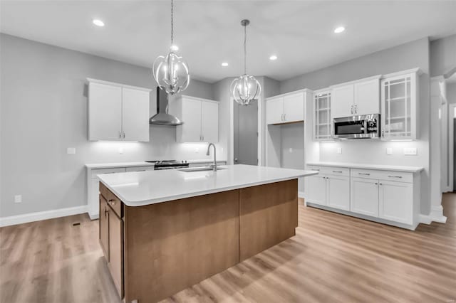 kitchen featuring white cabinets, wall chimney exhaust hood, sink, and appliances with stainless steel finishes