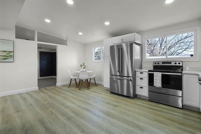 kitchen with light hardwood / wood-style flooring, white cabinets, and appliances with stainless steel finishes