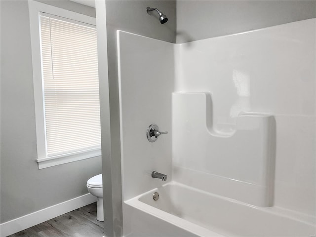 bathroom featuring wood-type flooring, shower / bathtub combination, and toilet