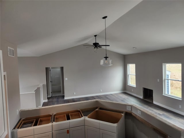 kitchen with ceiling fan, hardwood / wood-style flooring, a fireplace, white cabinetry, and lofted ceiling