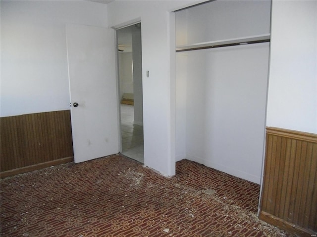 unfurnished bedroom featuring wooden walls and a closet