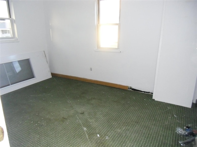 unfurnished living room with dark colored carpet and a wealth of natural light