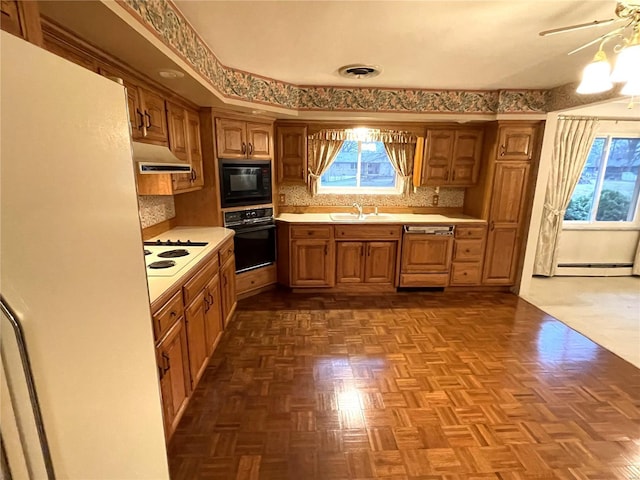 kitchen featuring tasteful backsplash, parquet floors, baseboard heating, sink, and black appliances