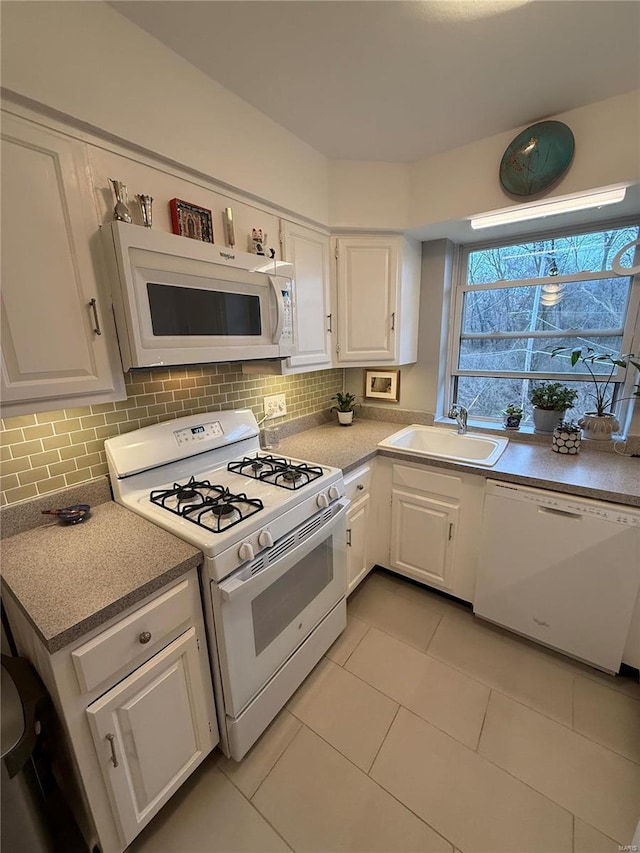 kitchen with white cabinetry, light tile patterned flooring, white appliances, and sink