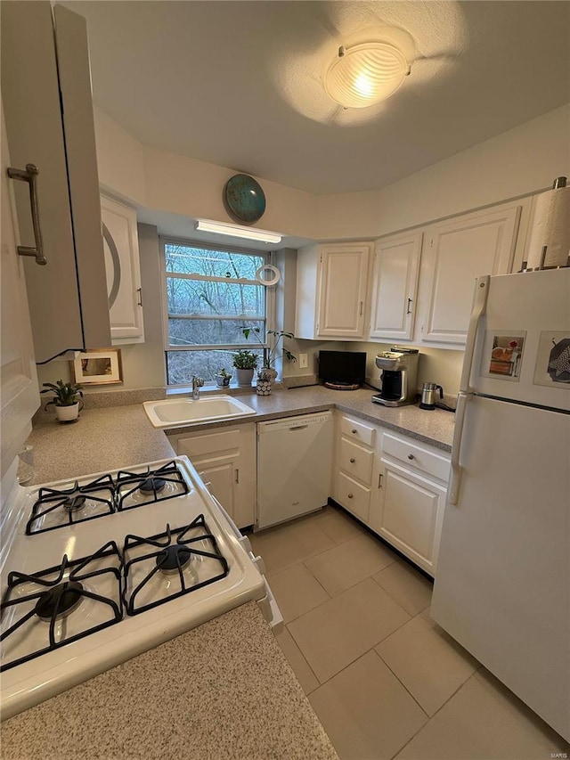 kitchen with sink, white cabinets, light tile patterned flooring, and white appliances