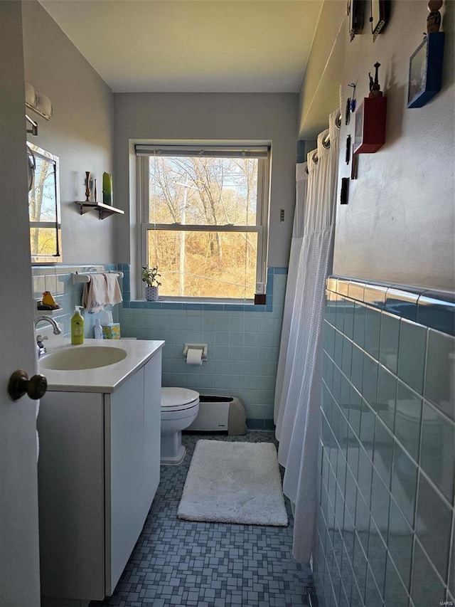 bathroom featuring tile patterned flooring, toilet, tile walls, and a wealth of natural light