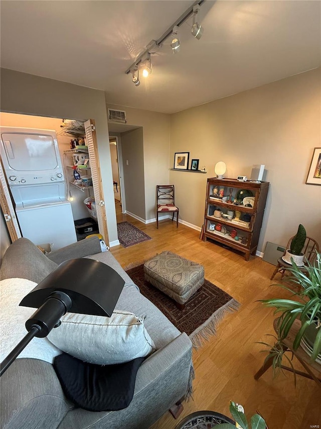 living room featuring light wood-type flooring, stacked washer and dryer, and track lighting