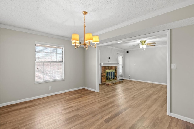 unfurnished living room featuring ceiling fan with notable chandelier, crown molding, hardwood / wood-style flooring, a fireplace, and a textured ceiling