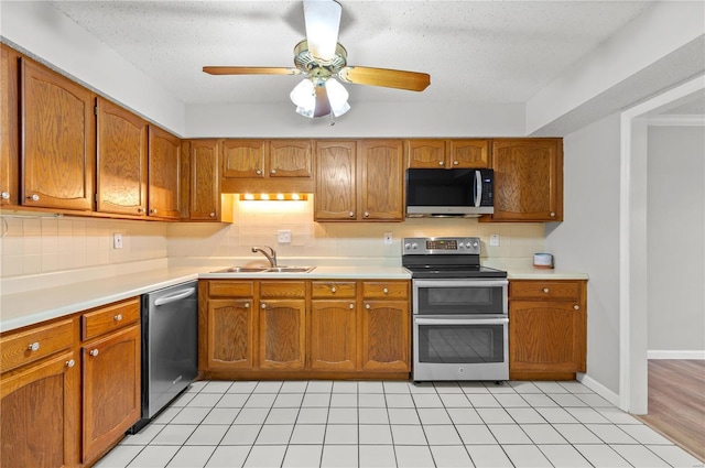 kitchen featuring sink, ceiling fan, light tile patterned floors, a textured ceiling, and stainless steel appliances