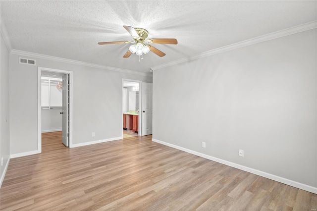 unfurnished bedroom with a walk in closet, a closet, ceiling fan, and ornamental molding