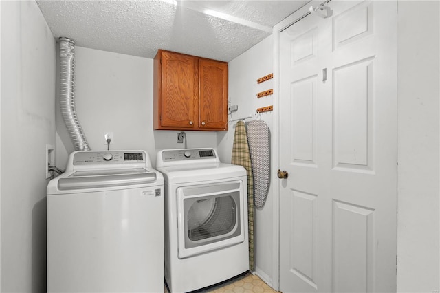 clothes washing area with washer and dryer, cabinets, and a textured ceiling