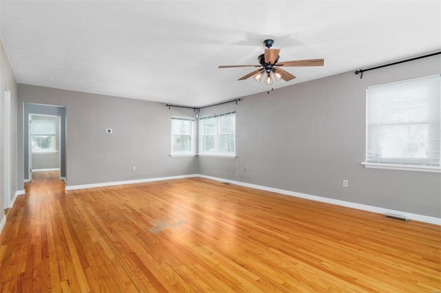 empty room with light hardwood / wood-style floors, a wealth of natural light, and ceiling fan