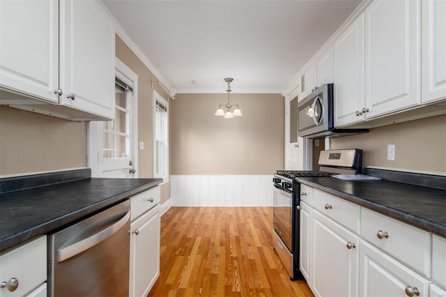 kitchen featuring crown molding, white cabinets, pendant lighting, and appliances with stainless steel finishes