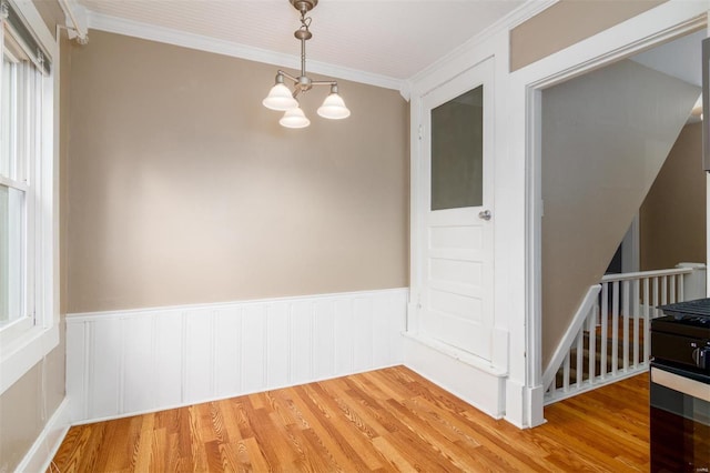 empty room featuring wood-type flooring, an inviting chandelier, and crown molding