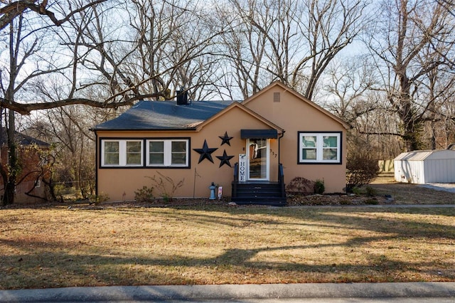 view of front of house with a front yard and a storage shed