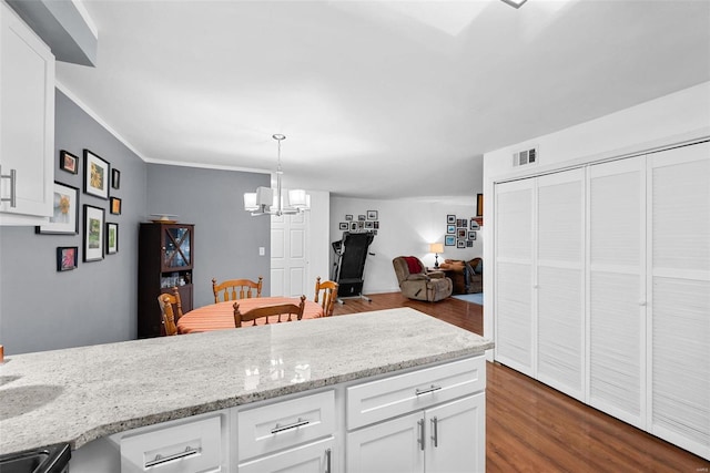 kitchen featuring an inviting chandelier, white cabinets, hanging light fixtures, dark hardwood / wood-style floors, and light stone countertops