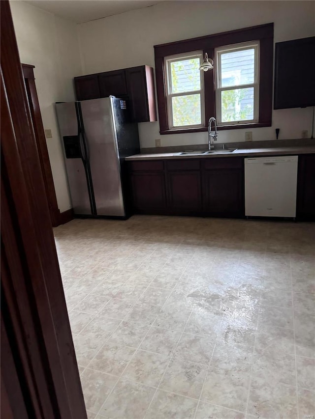 kitchen with stainless steel fridge with ice dispenser, dark brown cabinetry, white dishwasher, and sink