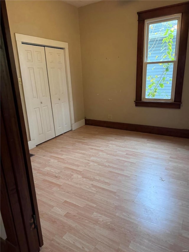 unfurnished bedroom with a closet and light hardwood / wood-style floors