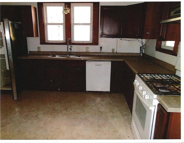 kitchen with pendant lighting, white appliances, range hood, and sink