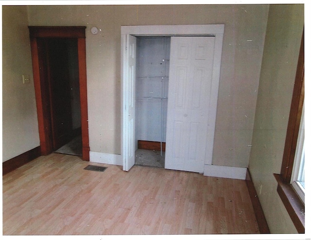 unfurnished bedroom with light hardwood / wood-style flooring and a closet