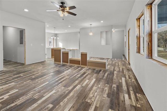 unfurnished living room featuring electric panel, dark hardwood / wood-style flooring, and ceiling fan with notable chandelier