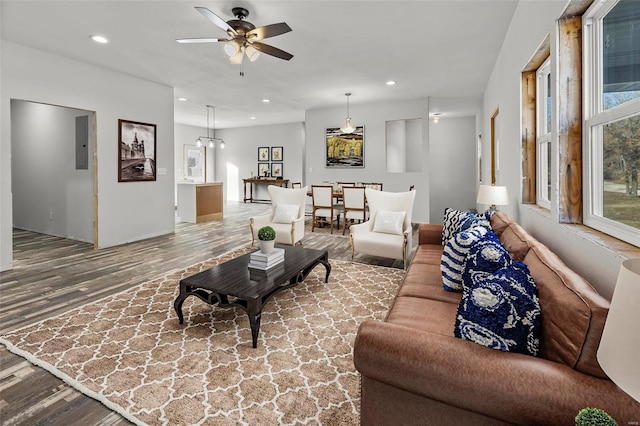 living room featuring hardwood / wood-style floors, ceiling fan with notable chandelier, and electric panel