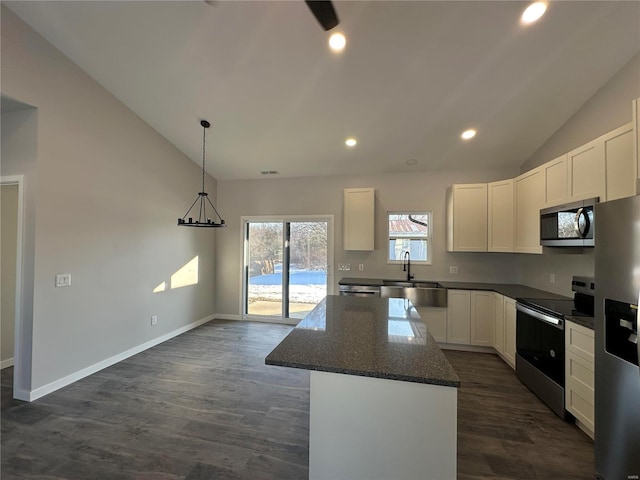 kitchen with vaulted ceiling, a center island, white cabinets, and appliances with stainless steel finishes