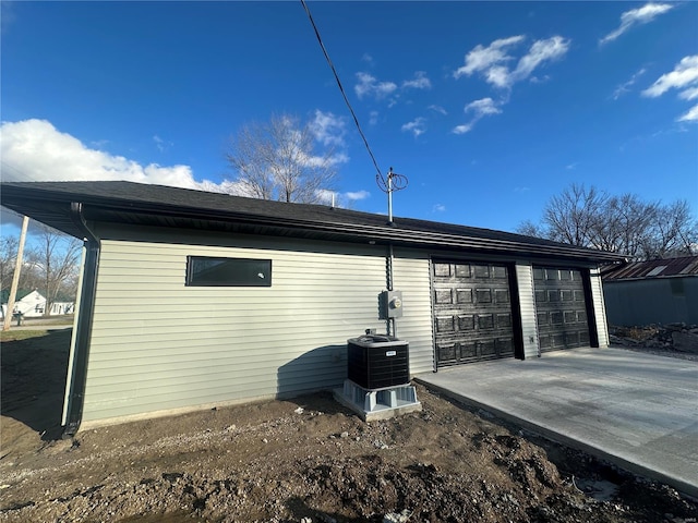 rear view of property featuring a garage, an outbuilding, and central AC unit