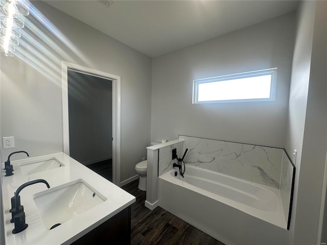 bathroom featuring vanity, hardwood / wood-style floors, a washtub, and toilet