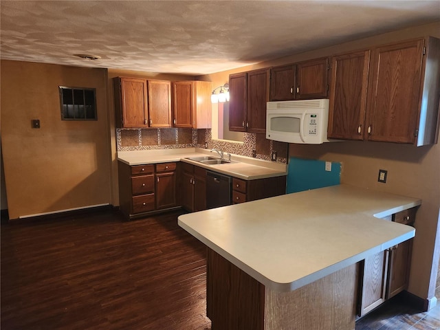 kitchen featuring dishwasher, sink, dark wood-type flooring, backsplash, and kitchen peninsula