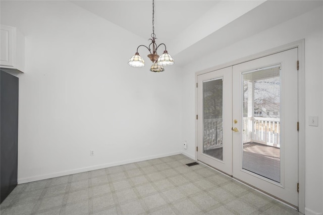 unfurnished dining area featuring a chandelier, french doors, and light carpet