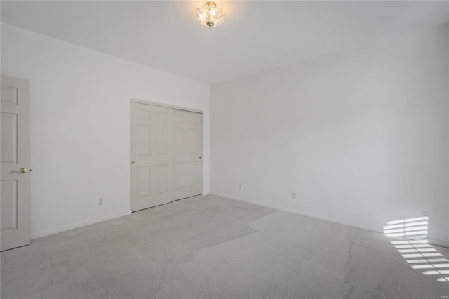 unfurnished bedroom with light carpet and a closet