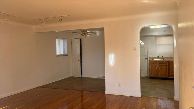 spare room featuring track lighting, ceiling fan, dark wood-type flooring, and sink