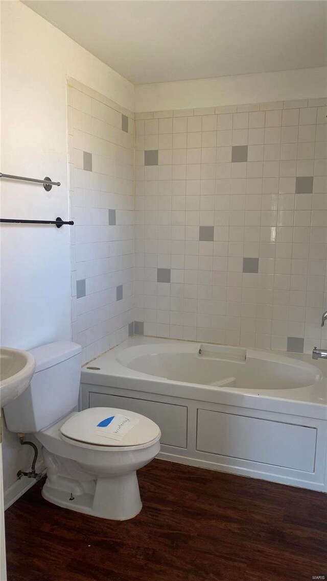 bathroom with tiled shower / bath, wood-type flooring, and toilet