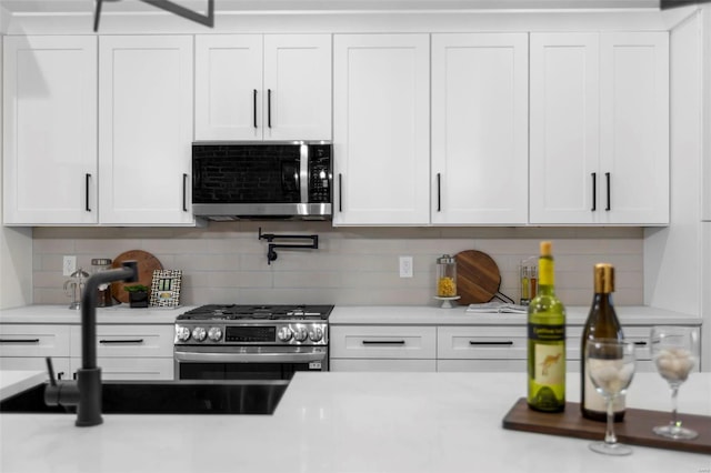 kitchen with backsplash, white cabinetry, sink, and stainless steel appliances