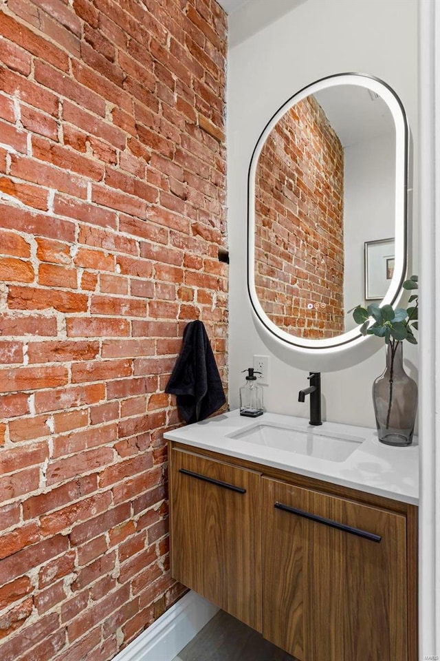 bathroom with vanity and brick wall