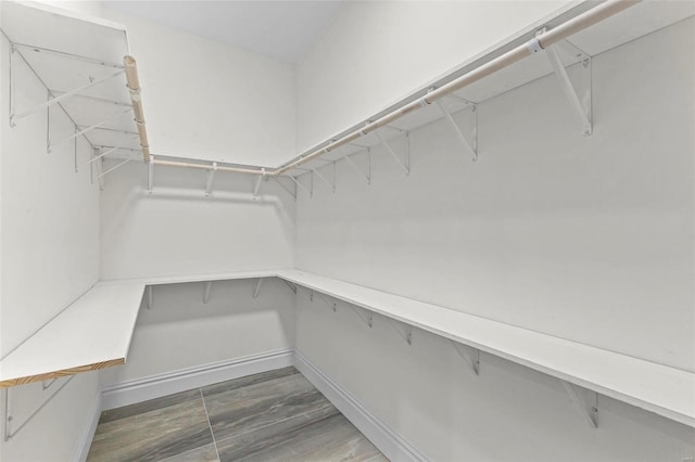 walk in closet with dark wood-type flooring