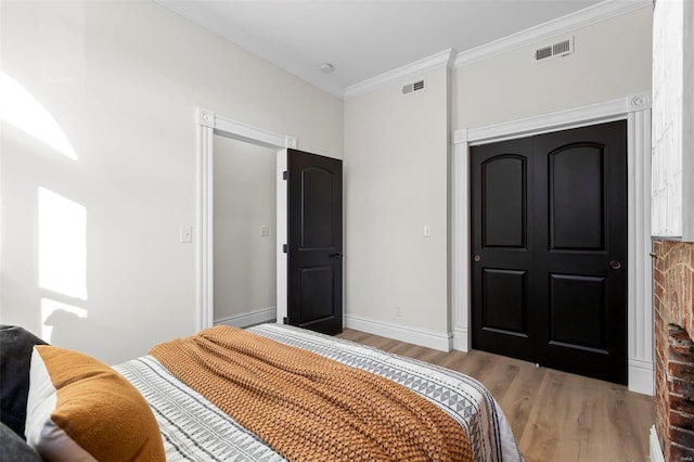 bedroom with a closet, light hardwood / wood-style flooring, and ornamental molding