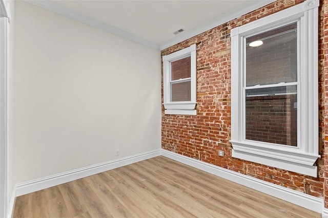 unfurnished room featuring crown molding, brick wall, and hardwood / wood-style flooring