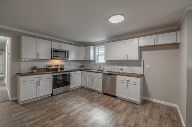 kitchen with butcher block counters, sink, stainless steel appliances, wood-type flooring, and white cabinets