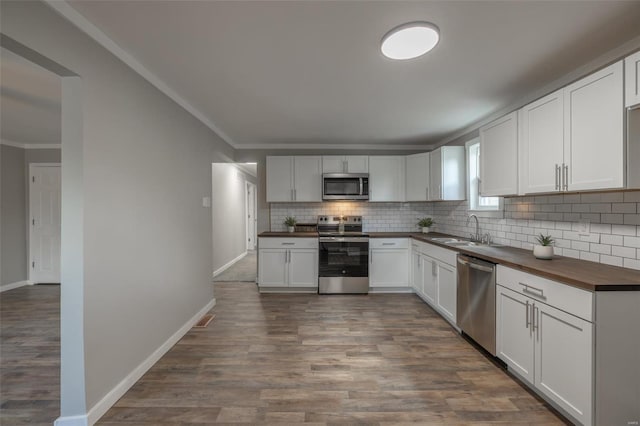 kitchen with wood counters, dark hardwood / wood-style flooring, stainless steel appliances, sink, and white cabinets