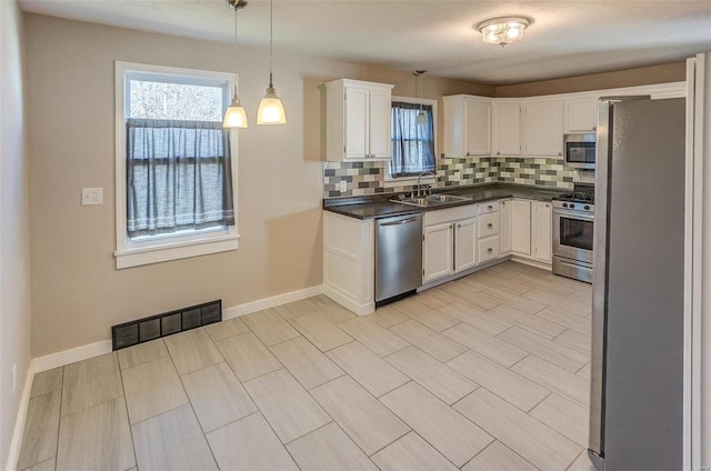 kitchen featuring white cabinets, pendant lighting, stainless steel appliances, and tasteful backsplash