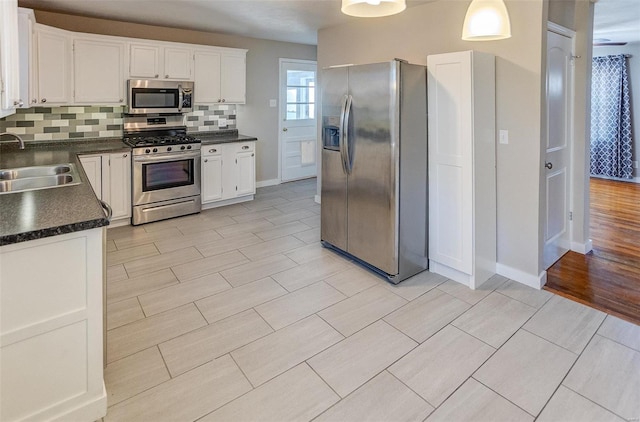 kitchen with white cabinetry, sink, hanging light fixtures, tasteful backsplash, and appliances with stainless steel finishes