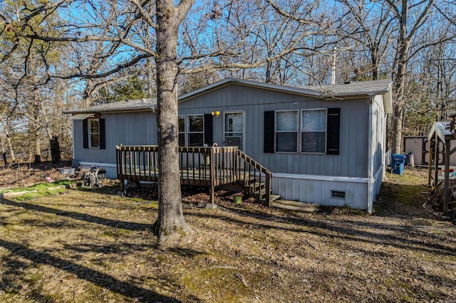 manufactured / mobile home featuring a wooden deck, a front yard, and a storage unit