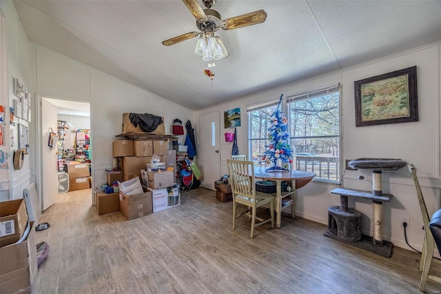 dining room with ceiling fan, wood-type flooring, and vaulted ceiling